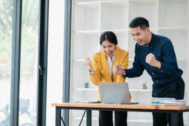 Modern ofis ortamında başarılı bir projeyi kutlayan iki iş arkadaşı, sevinç ve heyecanı ifade ediyorlar..