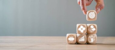 Hedefleri, stratejiyi ve başarıyı temsil eden simgelerle ahşap blokları istiflemenin kavramsal görüntüsü. İş, planlama ve başarı temaları için ideal.