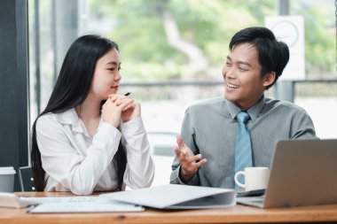 İki iş arkadaşı modern ofis ortamında doğal ışık ve yeşillik ile dışarıda tartışıyorlar..