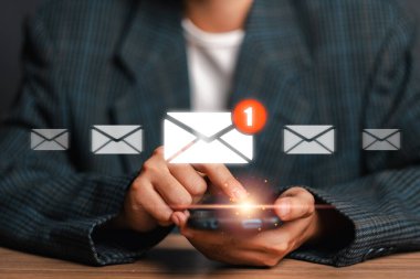 Yeni bir e-posta bildirim simgesi gösteren, modern iletişim ve teknolojiyi temsil eden bir akıllı telefon ile etkileşime giren bir kişi.