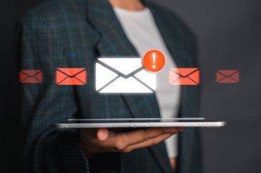 Ünlem işaretli dijital zarf, e-posta güvenlik uyarısını sembolize ediyor, takım elbiseli bir kişi tarafından tutuluyor..