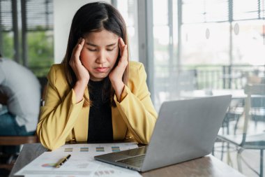 Sarı ceketli genç bir iş kadını, bir kafede dizüstü bilgisayarı ve masada bir kalemle çalışırken strese girdi..