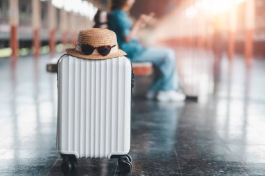 A white suitcase with a straw hat and sunglasses at a train station, capturing the essence of travel and adventure. clipart