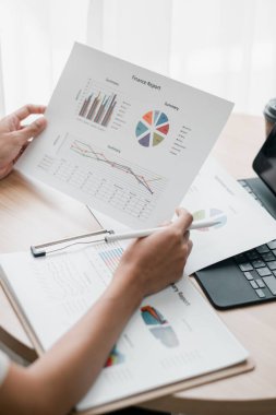 Finansal raporları grafik ve grafiklerle tutan ellerin yakın çekimi, profesyonel ofis ortamında veri analizi gösterilmesi.