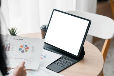 Bir iş adamı, kağıt üzerinde mali raporları ve modern ofis ortamında dijital tableti inceler..