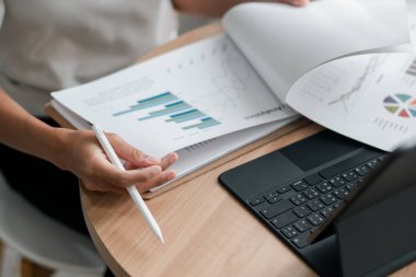 Finansal tabloları ve grafikleri kağıt ve dizüstü bilgisayarda inceleyen, veri analizi ve iş stratejisini vurgulayan bir kişinin yakın çekimi.