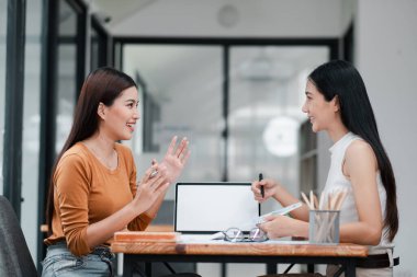 Çağdaş ofis ortamında verimli bir iş görüşmesi yapan iki kadın takım çalışması ve işbirliği sergiliyor..