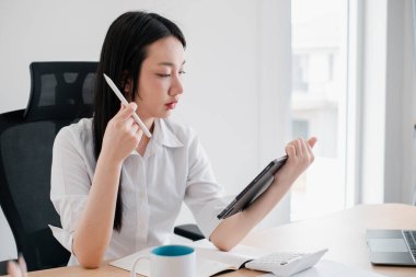Çağdaş bir ofis ortamında veri analizi için tablet kullanan odaklanmış iş kadını.