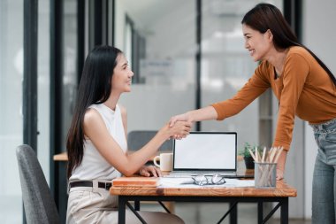 Modern ofis ortamında iki kadın iş görüşmesi sırasında profesyonel olarak el sıkışır..