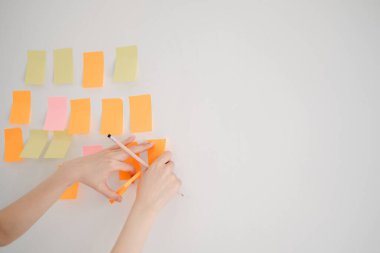 Duvarda canlı yapışkan notlar düzenleyen eller, modern ofis ortamında beyin fırtınası, organizasyon ve yaratıcılık kavramları için idealdir..
