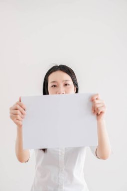Boş bir sayfa sunan kadın, basit beyaz bir arkaplan karşısındaki tasarım ya da tasarım sunumları için ideal..