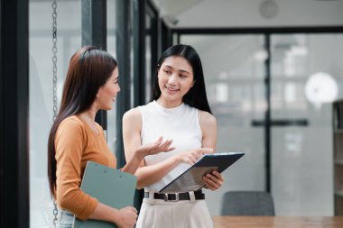 Modern bir ofiste, cam duvarları olan, takım çalışması ve işbirliği sergileyen iki genç kadın iş görüşmesi yaptılar..