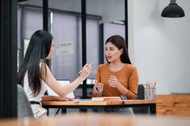 Modern ofis ortamında iş stratejilerini tartışan iki kadın, takım çalışması ve profesyonel iletişim.