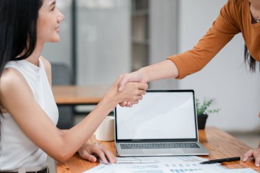 Çağdaş ofis ortamında el sıkışarak anlaşma imzalayan iki profesyonel kadın..