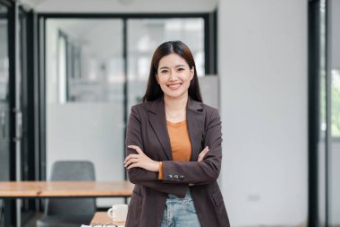 Modern bir ofiste gülümseyen bir iş kadını, profesyonel kıyafetler giyiyor, kendine güveni ve yaklaşımı yayıyor..