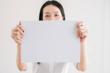 Parlak ve minimalist bir ortamda, özel metin ya da grafikler eklemek için mükemmel beyaz bir işaret sunan kadın.