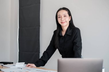 Modern bir ofiste profesyonel bir kadın, kendine güvenen, dizüstü bilgisayarlı bir masada duran, profesyonellik saçan ve odaklanan..