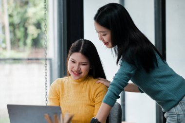 İki genç kadın bir dizüstü bilgisayarda çalışıyor, fikirleri paylaşıyor ve modern bir ev ortamında verimli bir seansın tadını çıkarıyor..