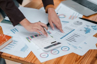 İş analizi ve finansal planlamayı temsil eden, hesap makinesi kullanan ve mali tabloları inceleyen ellerin yakın plan çekimi.