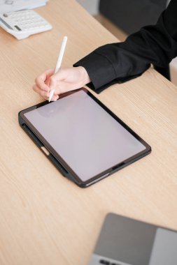 El ele tutuşma stili, ahşap bir masada dijital tabletle etkileşim, çalışma alanında modern teknolojiyi sergilemek..