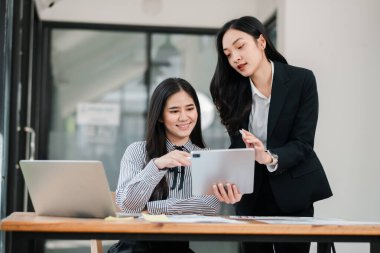 * * Modern bir ofiste iki iş kadını dijital tablet ve dizüstü bilgisayar kullanarak fikirleri tartışıyor ve işbirliği yapıyorlar.