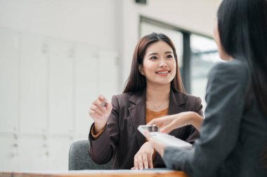 Modern ofis ortamında fikirleri tartışan iki kadın profesyonel etkileşim ve takım çalışması sergiliyor..