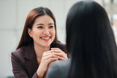 İki kadın, modern ofis ortamında profesyonel etkileşim ve iletişim sergileyen dostane bir iş toplantısına katıldı..