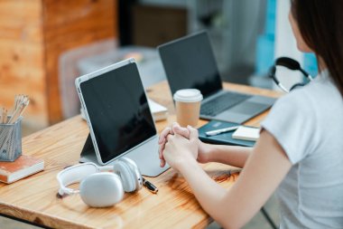 Bir tablet, dizüstü bilgisayar, kulaklık ve kahve fincanının yer aldığı modern bir ofis masası, çağdaş bir çalışma ortamı sunuyor..
