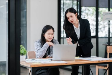 Modern ofis ortamında bir dizüstü bilgisayar ve belge kullanarak bir proje üzerinde çalışan iki iş kadını..