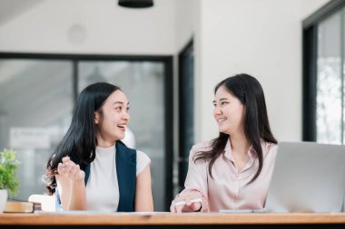 Masada dizüstü bilgisayarla gülümseyen ve konuşan iki kadın..