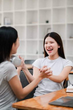 Bir kafede gülüp sohbet eden iki kadın neşeli ve dostane bir ortam yaratıyor..