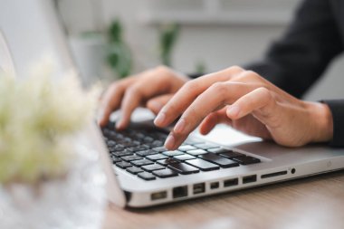 Modern ofis ortamında dizüstü bilgisayarda yazan eller üretkenliği ve teknolojiyi gösteriyor..