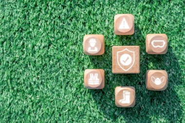 Wooden blocks with safety symbols on grass, illustrating essential work safety concepts and precautions. clipart