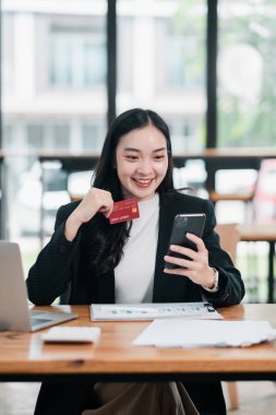 Samimi bir kafe ortamında online alışveriş için akıllı telefon ve kredi kartı kullanan gülümseyen bir kadın..