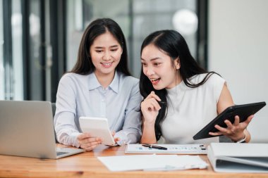 Çağdaş bir ofis ortamında dijital cihazlar kullanarak işbirliği yapan iki profesyonel kadın..