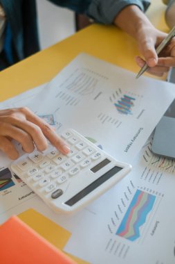 Bir hesap makinesi kullanarak ve finansal tabloları inceleyerek ellerinizi yakın plan yapın, iş, finans ve analiz konuları için ideal.