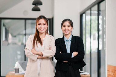 Modern ofis ortamında iki profesyonel kadın, güven ve takım çalışması yayıyorlar..