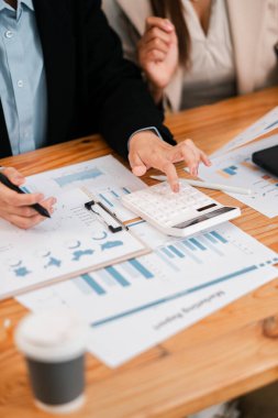 Ekonomik tabloları inceleyen ve stratejik planlama için toplantı sırasında hesap makinesi kullanan bir iş adamı..