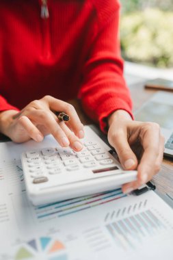 Finansal belgeler, iş analizleri ve muhasebe kavramları üzerinde hesap makinesi kullanarak ellerin yakın plan görüntüsü.