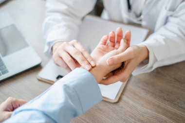 Bir doktor, modern bir klinik ortamında profesyonel sağlık hizmetleri sunan hastanın nabzını inceler..