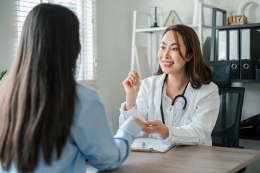 Kadın bir doktor, parlak, modern bir ofiste, profesyonel bir sağlık hizmeti sunan bir hastayla ilişki kurar..