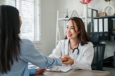 Parlak, modern bir muayenehane ortamında gülümseyen ve bir hastaya danışan bir kadın doktor..