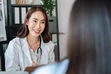 Gülümseyen kadın doktor modern bir muayenehanede bir hastayla meşgul oluyor, profesyonel sağlık hizmetleri etkileşimi sergiliyor..