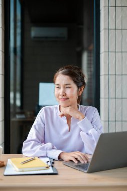 Modern bir ofiste kendine güveni tam bir kadın dizüstü bilgisayar üzerinde çalışıyor, verimliliği gösteriyor ve çağdaş bir çalışma alanına odaklanıyor..