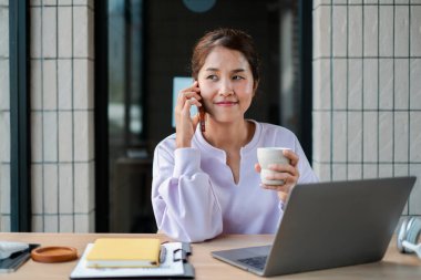 Günümüz ofis ortamında dizüstü bilgisayar üzerinde çalışırken birden fazla iş yapan kendine güvenen bir kadın..