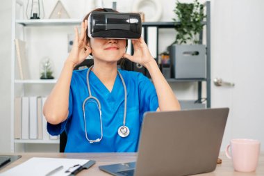 VR kulaklığını eğitim için kullanan, sağlık teknolojisinde yenilik sergileyen önlüklü bir tıp uzmanı..