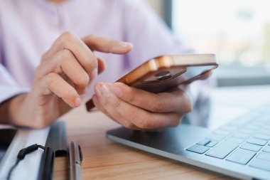 Eller akıllı telefon ve dizüstü bilgisayarla etkileşime girer, profesyonel bir ortamda modern teknoloji ve iletişimi sembolize eder..