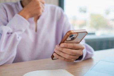 Lavanta kazaklı bir kadın kafeterya masasında dizüstü bilgisayarla akıllı telefon kullanıyor modern teknoloji ve günlük yaşam tarzını sergiliyor..