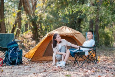 Bir anne ve oğul, doğa ve kamp malzemeleriyle çevrili bir ormanda kamp yaparken yakınlaşıyorlar..