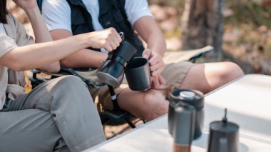 Arkadaşlar, doğa ve rahatlık içinde kamp yaparken taze demlenmiş kahvenin tadını çıkarıyorlar..